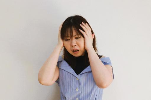 頭を抱える女性 頭痛,悩み,不安の写真素材