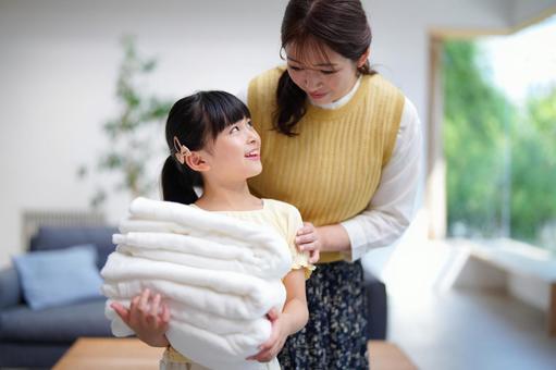 畳んだ洗濯物を持ち振り向く女の子 畳んだ洗濯物を持ち振り向く女の子 娘,振り向く,母の写真素材