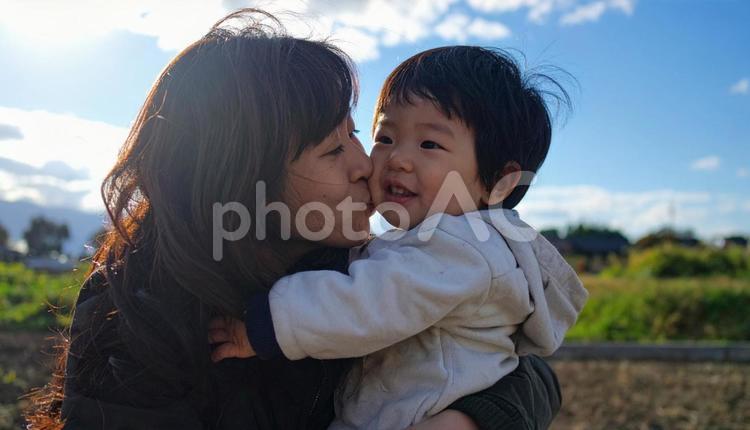 青空の下、子供を抱っこする母親 親子,母親,母子の写真素材