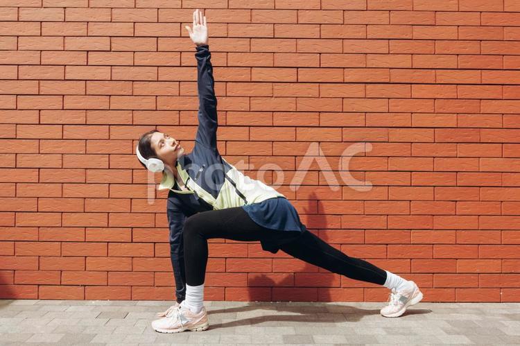 足に手を付けて手を180度伸ばす女性 女性,準備運動,ヘッドフォンの写真素材