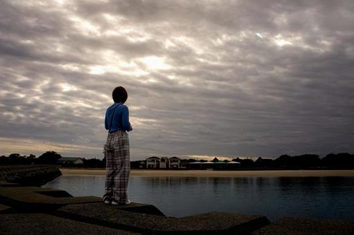 ＜素材＞夕暮れの海辺を散策する女性 女性,悩む,海の写真素材