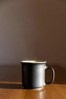 西日を浴びて湯気が立つコーヒー_縦 コーヒー,湯気,珈琲の写真素材