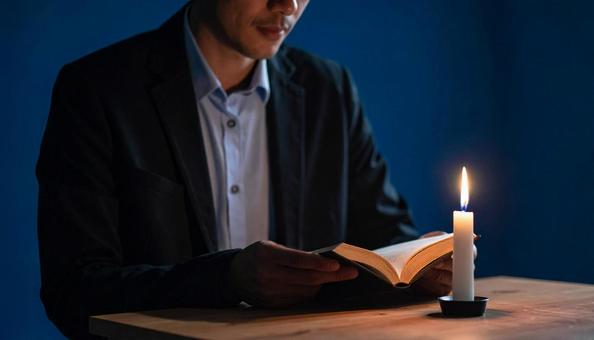 蝋燭の灯りで本を読む男性 蝋燭の灯りで本を読む男性の写真