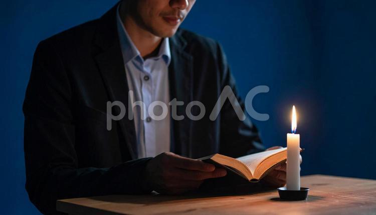 蝋燭の灯りで本を読む男性 男性,本,読書の写真素材