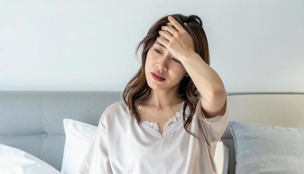 冷房が寒くて額に手をやる体調不良の女性の写真