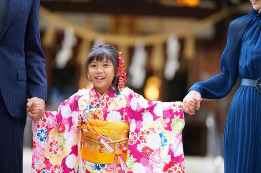 七五三参りで家族と手をつなぐ晴れ着の少女 七五三参りで家族と手をつなぐ晴れ着の少女の写真
