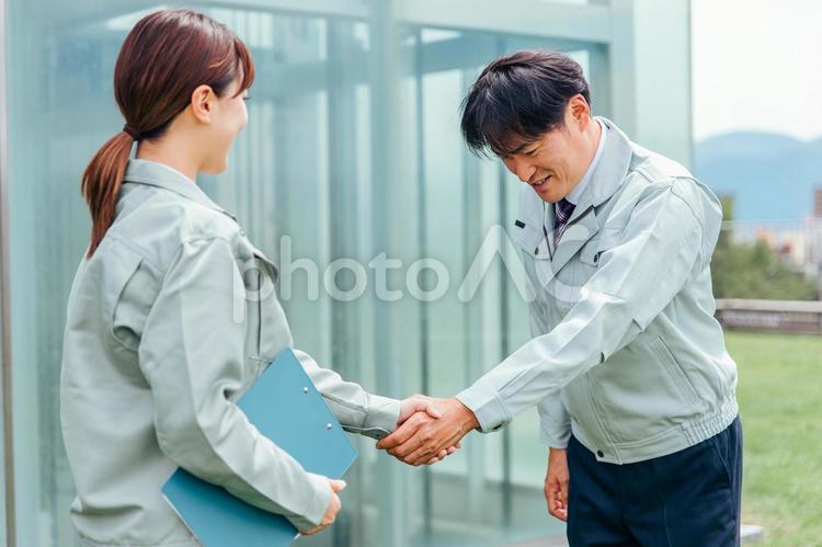 握手する作業着姿の男女（契約） 握手,契約,作業服の写真素材