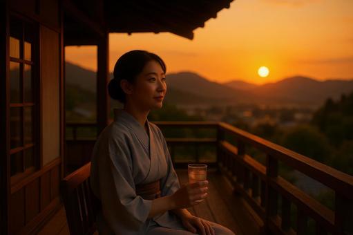 テラスで夕日を眺める女性 テラスで夕日を眺める女性の写真