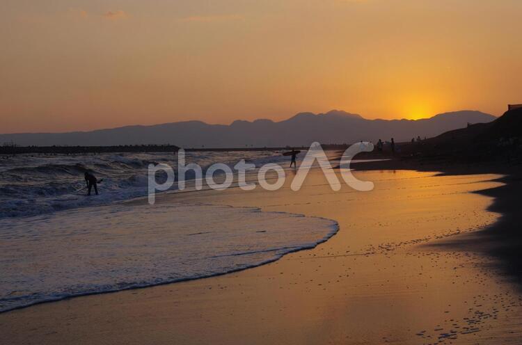 夕暮れのビーチ、奥の方にサーファー 夕暮れ,夕焼け,海の写真素材