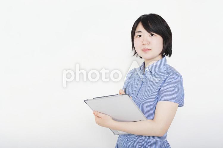 ヒアリングしてチェックするワンピースを着た女性 メモ,記録,女性の写真素材