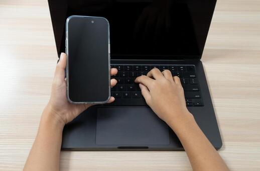 ノートパソコンとスマートフォンを操作する スマートフォン,ノートパソコン,手元の写真素材