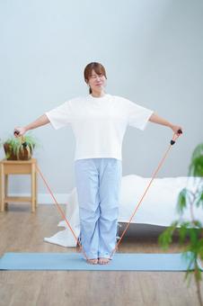 トレーニングチューブを両手で引っ張る女性の写真