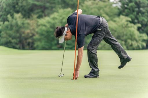 カップからボールを取り出す男性ゴルファー カップからボールを取り出す男性ゴルファー ゴルフ,カップイン,パターの写真素材