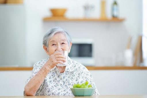 座ってコップを持つ高齢女性 女性,水,飲むの写真素材