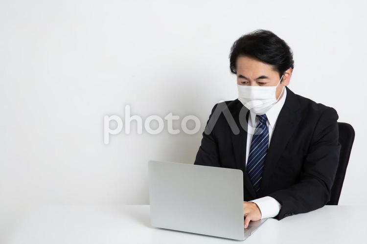 マスクをしながら仕事をしている中年のサラリーマン男性（コピースペース） 中年,上司,会社員の写真素材