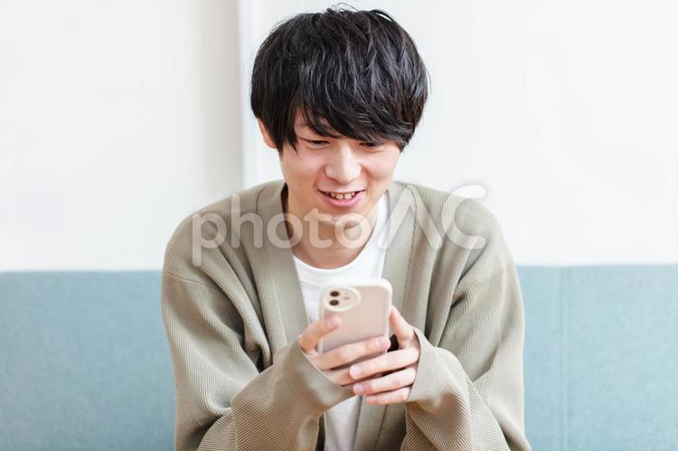 笑顔でスマホを操作する男性　 男性,スマホ,携帯電話の写真素材