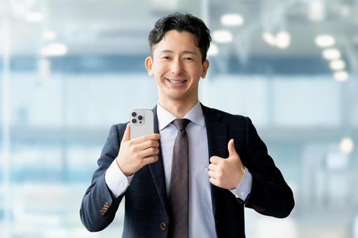 スマホを持っていいね!のポーズをする男性 スマホを持っていいね!のポーズをする男性 男性,スマホ,笑顔の写真素材