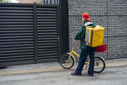 配達先に自転車で来た配達バッグを背負ったフードデリバリーの男性 配達,フードデリバリー,デリバリーの写真素材