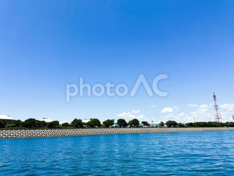 海から望む工業地帯の建物と緑の木々 波,海,青空の写真素材