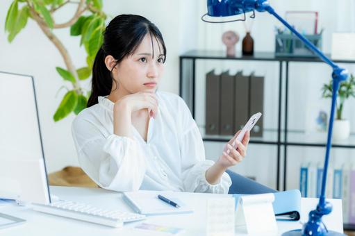 スマホを見ながら考えるビジネスウーマン スマホ,考える,悩むの写真素材