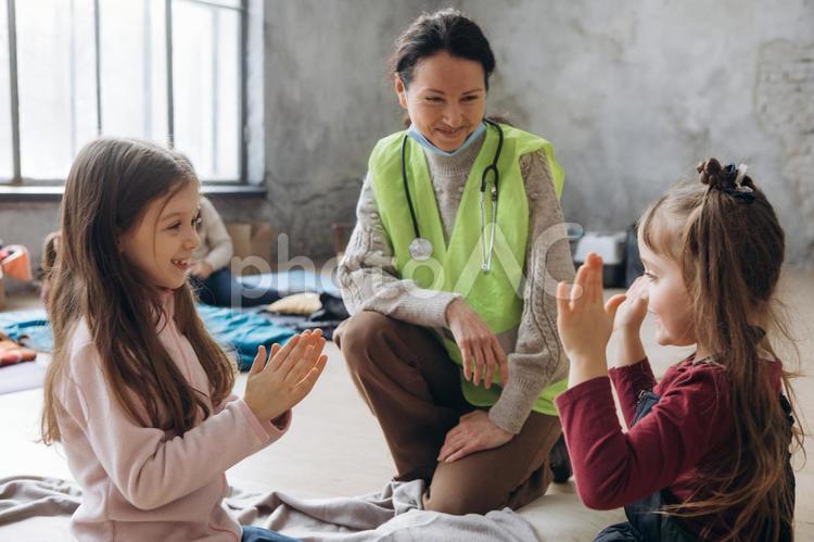 遊んでる女の子たちを笑顔で見守る女性 女性,女の子,人物の写真素材