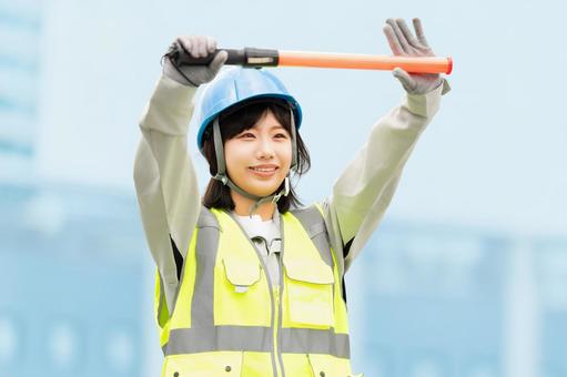 工事現場で交通誘導をする若い女性 工事現場で交通誘導をする若い女性の写真