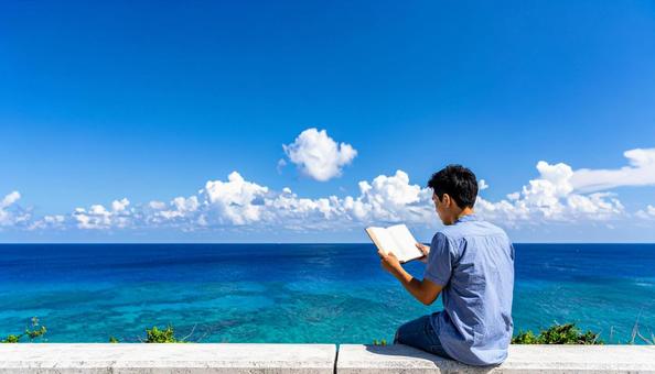 青空の下で本を読む日本人男性 青空の下で本を読む日本人男性の写真