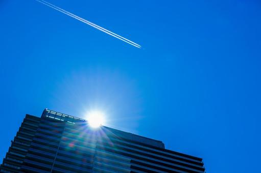 マンションの上空を飛ぶ旅客機と飛行機雲 マンションの上空を飛ぶ旅客機と飛行機雲の写真