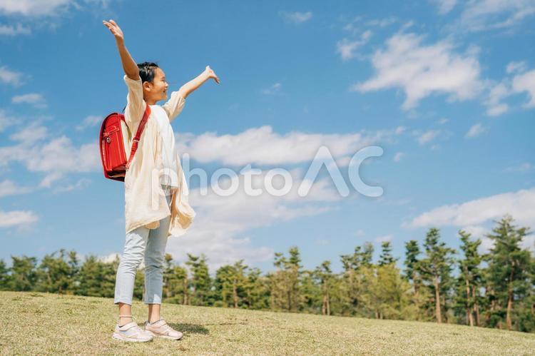 芝生の上でバンザイする小学生 小学生,子供,笑顔の写真素材