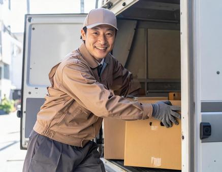 トラックから荷物を出す宅配男性ドライバー トラックから荷物を出す宅配男性ドライバーの写真