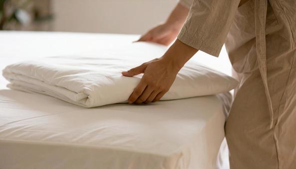 布団にカバーをかぶせている日本人女性 布団にカバーをかぶせている日本人女性の写真