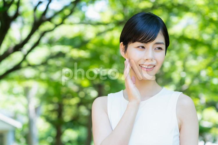 緑の中でスキンケアをする若い女性 スキンケア,ビューティー,女性の写真素材