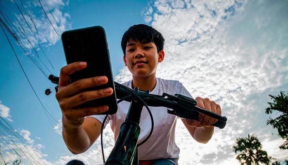 自転車を止めてスマホを見る男の子 自転車を止めてスマホを見る男の子の写真