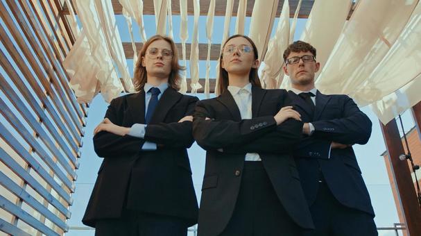 腕組みをする黒スーツの男女3人の写真