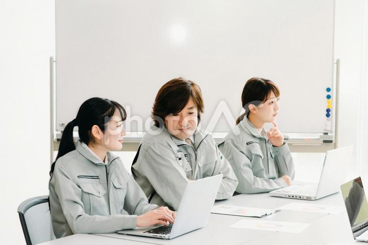 会議をする作業着をきた会社員（考える・3人） 作業服,開発,ビジネスの写真素材