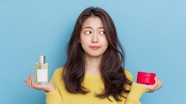 ヘアオイルとワックスで悩む女性 ヘアオイルとワックスで悩む女性の写真