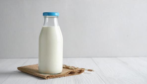 牛乳の入った牛乳瓶と白背景 牛乳の入った牛乳瓶と白背景の写真