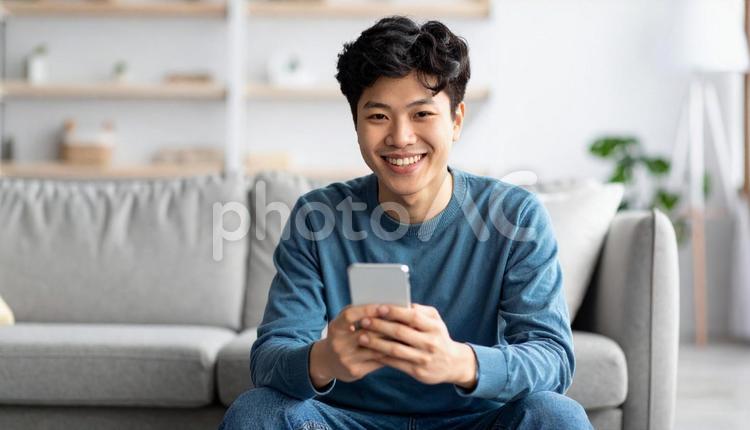 スマホを持ち笑顔の男性の室内ポートレート 人物,男性,10代の写真素材
