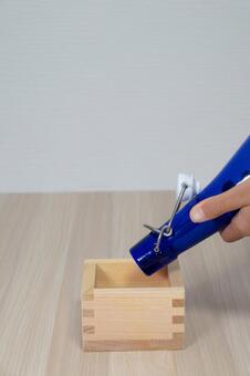 縦構図で枡に青い瓶から液体を注ぐ手元 縦構図,枡,青いの写真素材