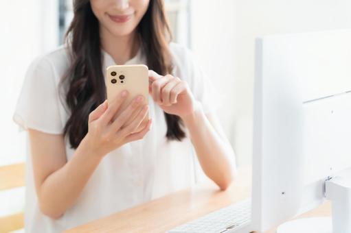 リビングでテレワークをする若い女性 リビングでテレワークをする若い女性の写真