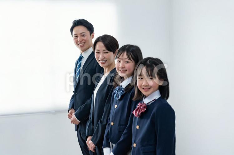 スーツを着た男女と制服を着た女の子二人 入学式,父母,母親の写真素材