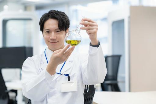 実験をする白衣の若い男性研究者 実験をする白衣の若い男性研究者の写真