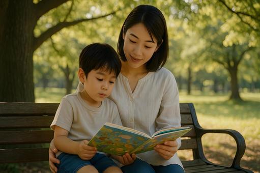 公園で絵本を読む親子の写真