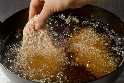 とんかつを油の中へ入れる瞬間 とんかつを油の中へ入れる瞬間 とんかつ,入れる,油の写真素材
