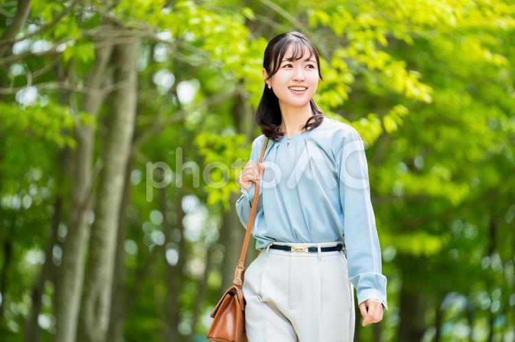 屋外を歩く笑顔の女性・ビジネスウーマン 女性,歩く,緑の写真素材