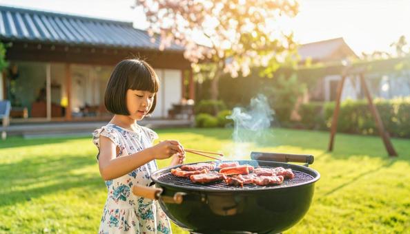 ホームパーティのBBQで焼肉を食べる子供 ホームパーティのBBQで焼肉を食べる子供の写真