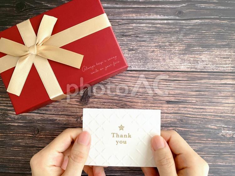 赤いプレゼントとサンキューカードを持つ手 プレゼント,メッセージカード,ありがとうの写真素材