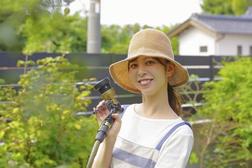 庭の植物に丁寧に水をあげる女性 庭の植物に丁寧に水をあげる女性 ガーデニング,水やり,水撒きの写真素材