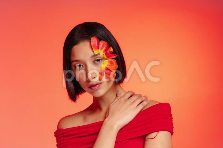 赤い花びらを顔に付けカメラ目線の女性 女性,フラワーメイク,花びらの写真素材