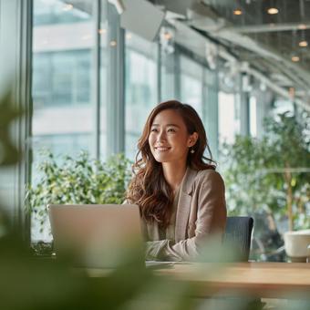 現代的なオフィスで笑顔で働く若い女性 現代的なオフィスで笑顔で働く若い女性の写真